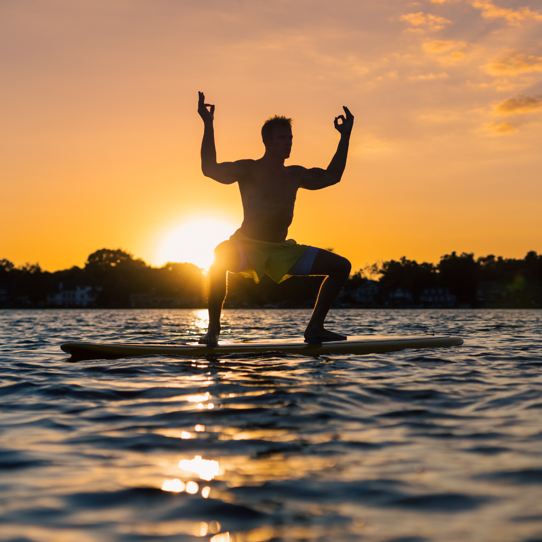 Male doing SUP Yoga at sunset