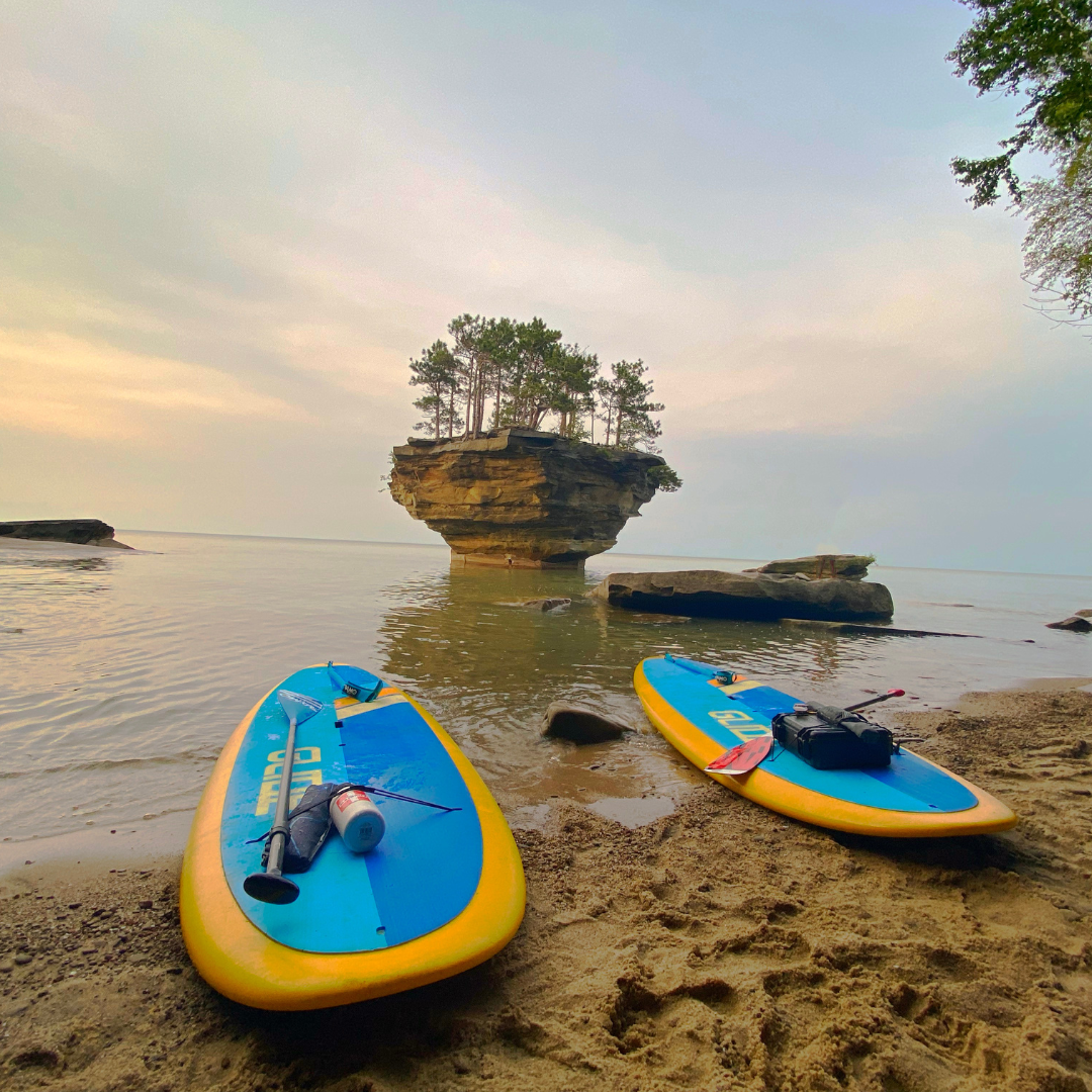 Michigan's Turnip Rock at sunset with paddle boards laying on beach